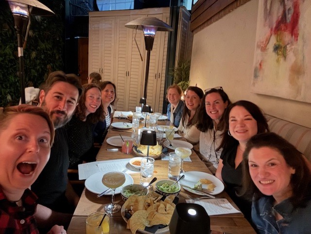 A selfie of Avalon’s senior leadership at a long table covered in appetizers.