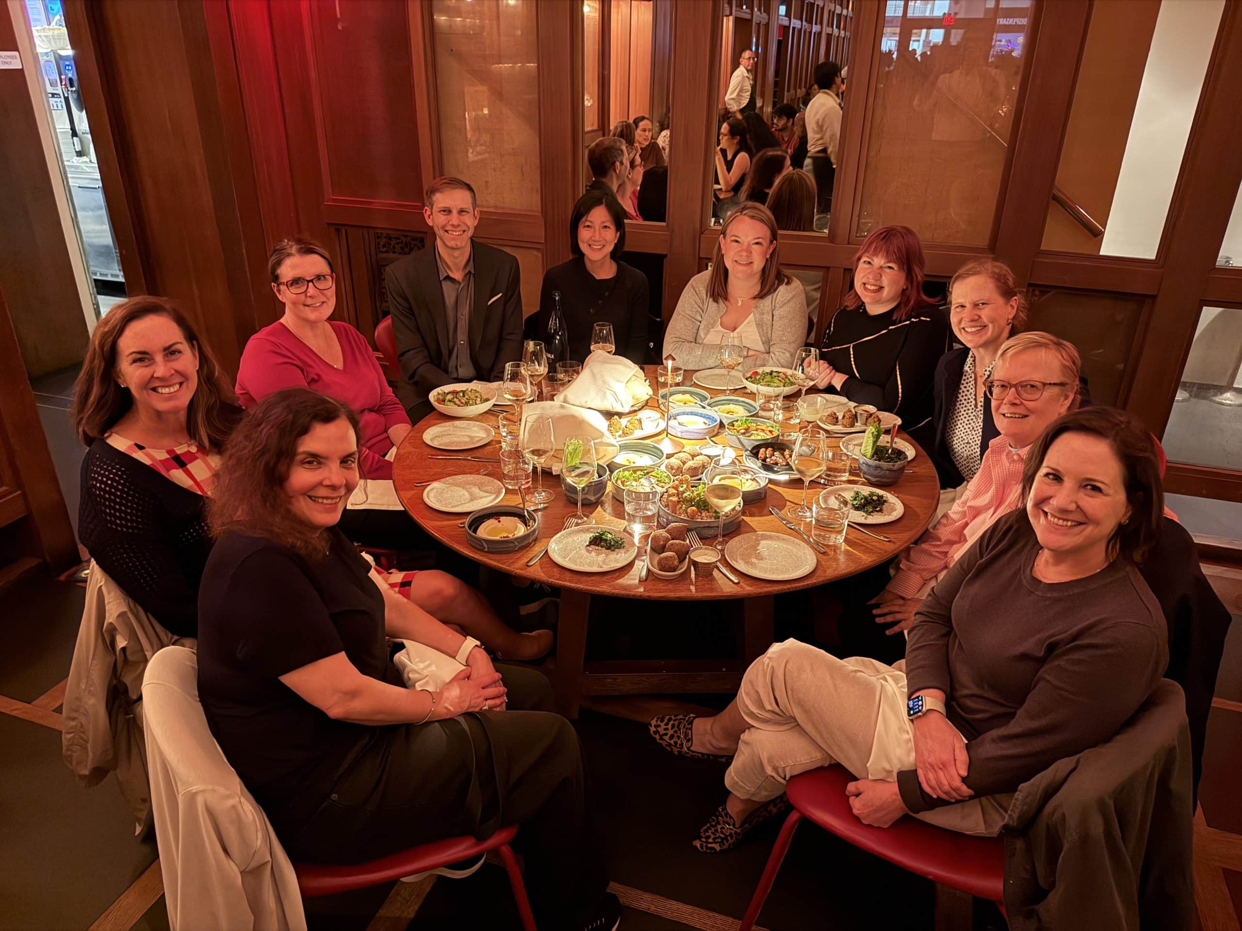 Photograph shows a group of Avalon leaders gathered around a round restaurant table for a shared dinner. 