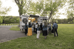 A group of people getting dessert at the ice cream truck.