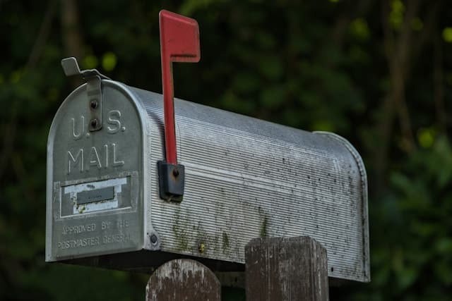 A weathered US mailbox with a red flag.